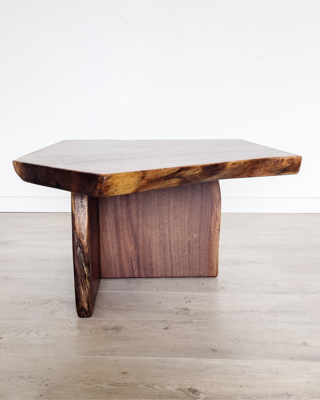 A wooden coffee table with a thick, irregularly shaped top and sturdy legs, showcasing a natural wood grain and texture. This piece of live edge furniture stands on a light wooden floor with a white wall background, embodying the latest in furniture trends. A wooden coffee table with a thick, irregularly shaped top and sturdy legs, showcasing a natural wood grain and texture. This piece of live edge furniture stands on a light wooden floor with a white wall background, embodying the latest in furniture trends.