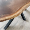 A close-up of the Ready To Ship - Black Walnut Live Edge Coffee Table, highlighting its natural wood grain and organic shape. The table features black metal legs and is set on a light-colored wood floor, perfect for instant style enhancement.