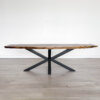 Introducing the Ready To Ship - Black Walnut Live Edge Coffee Table: a minimalist design crafted from rich black walnut wood and featuring black crisscross metal legs. This elegant piece is ready to ship and rests beautifully on a light gray hardwood floor against a plain white wall.