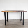 The Ready To Ship – Black Walnut Desk With H-Shaped Legs is a simple, modern rectangular table featuring a black walnut top and sleek black H-shaped metal legs. It is set on a wooden floor against a white wall and is ready for immediate shipping.