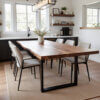 A modern dining room featuring a large wooden table with a live edge and six beige upholstered chairs. The room has white walls, large windows with natural light, a minimalist light fixture, and shelves with decor items. A beige rug lies under the table.